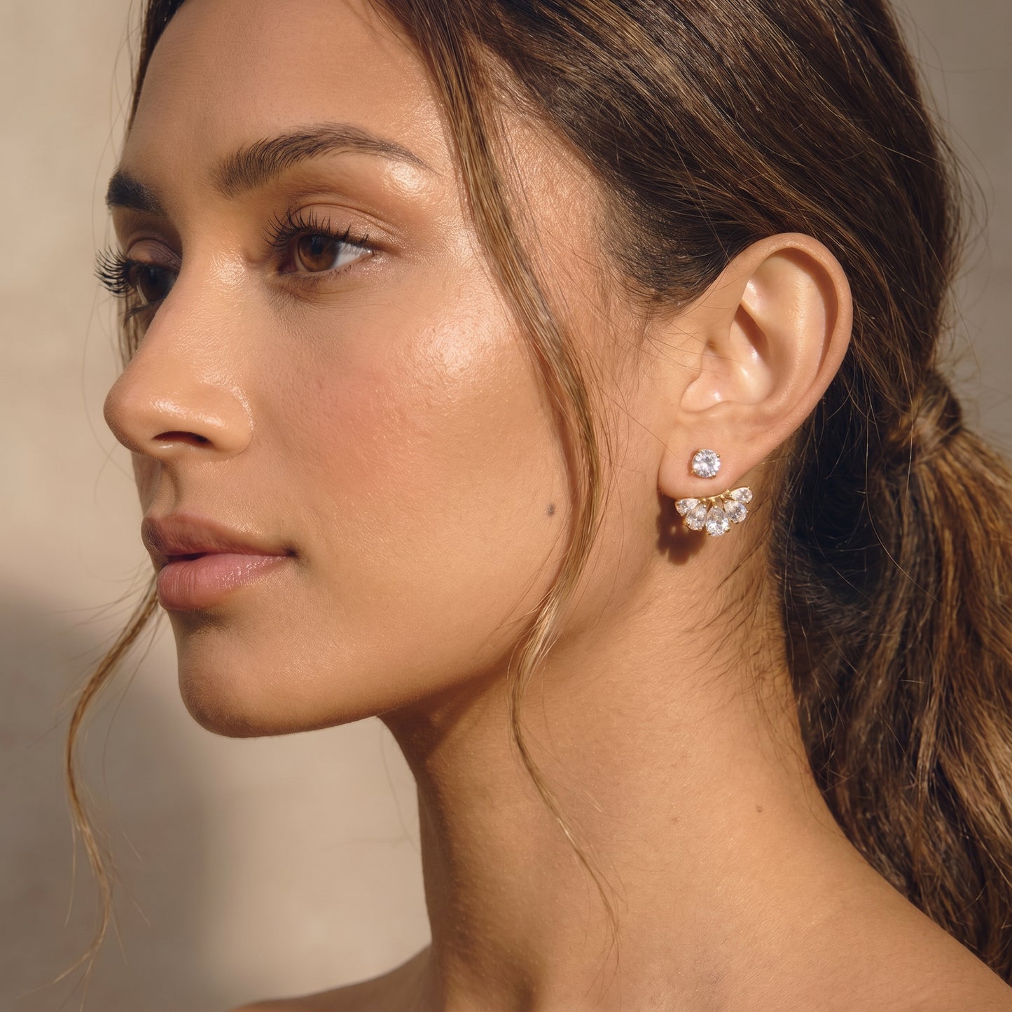 High quality waterproof gold plated 2-in-1 convertible fan earrings featuring a round solitaire stud and an interchangeable fanned crescent of clear crystals worn by a women.