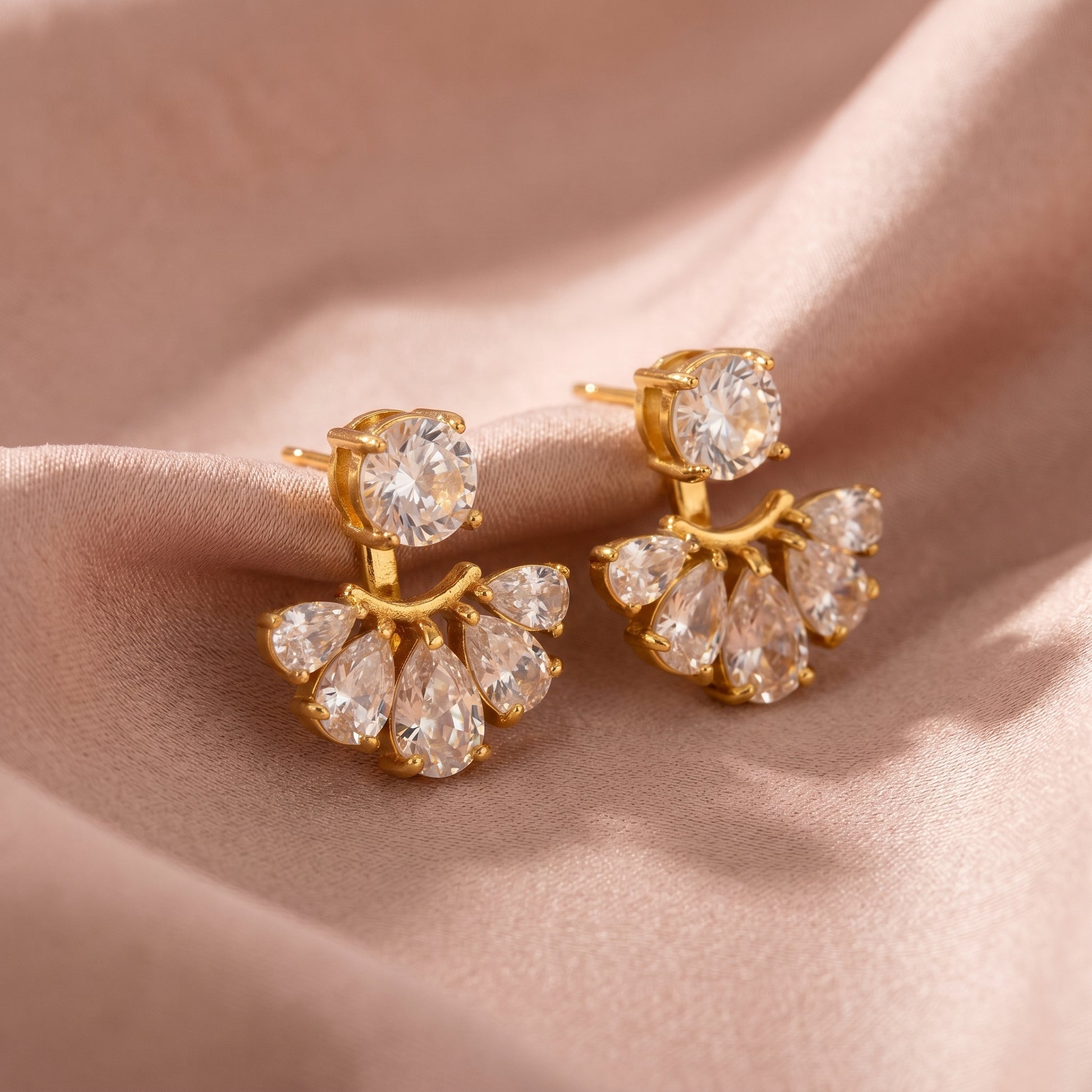 High quality waterproof gold plated 2-in-1 convertible fan earrings featuring a round solitaire stud and an interchangeable fanned crescent of clear crystals, on a clean beige fabric background