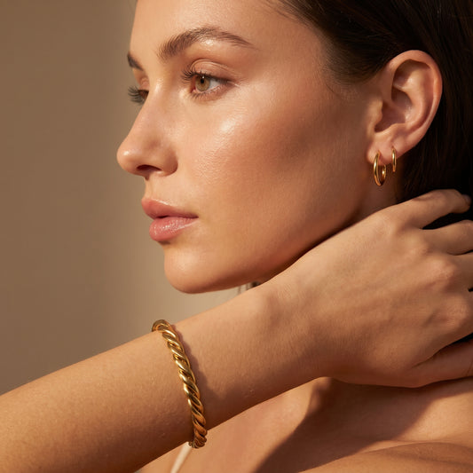 Close-up of a woman wearing high quality Sienne Twisted Cuff Bangle by Floravisha against a neutral background.