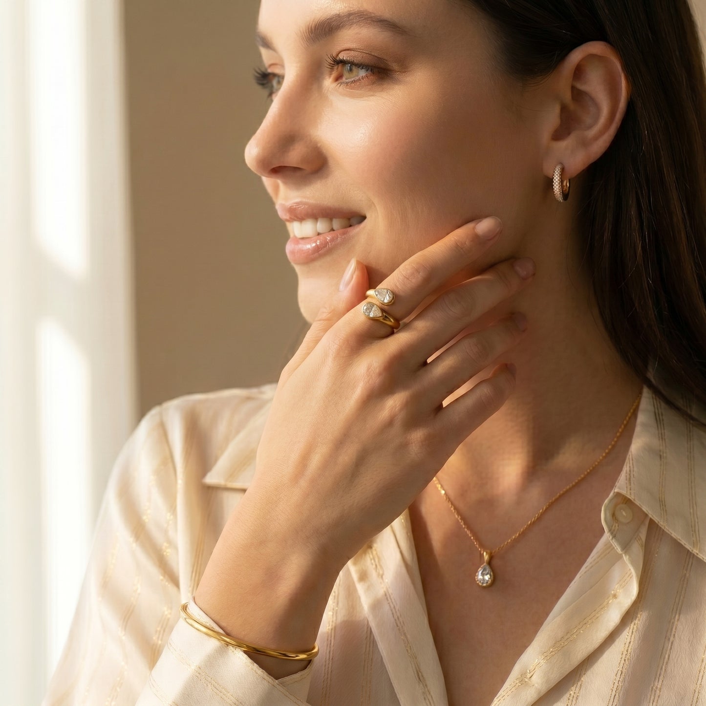 Woman wearing a Soleil Toi et Moi Adjustable Ring by Floravisha. A high quality, waterproof gold plated open wrap ring featuring two brilliant teardrop-cut clear crystals. Elegant, tarnish-free, and skin friendly with a neutral background.