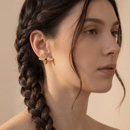 Side portrait of a woman wearing the statement waterproof Abeille gold pavé bee earrings styled with an elegant side braid.