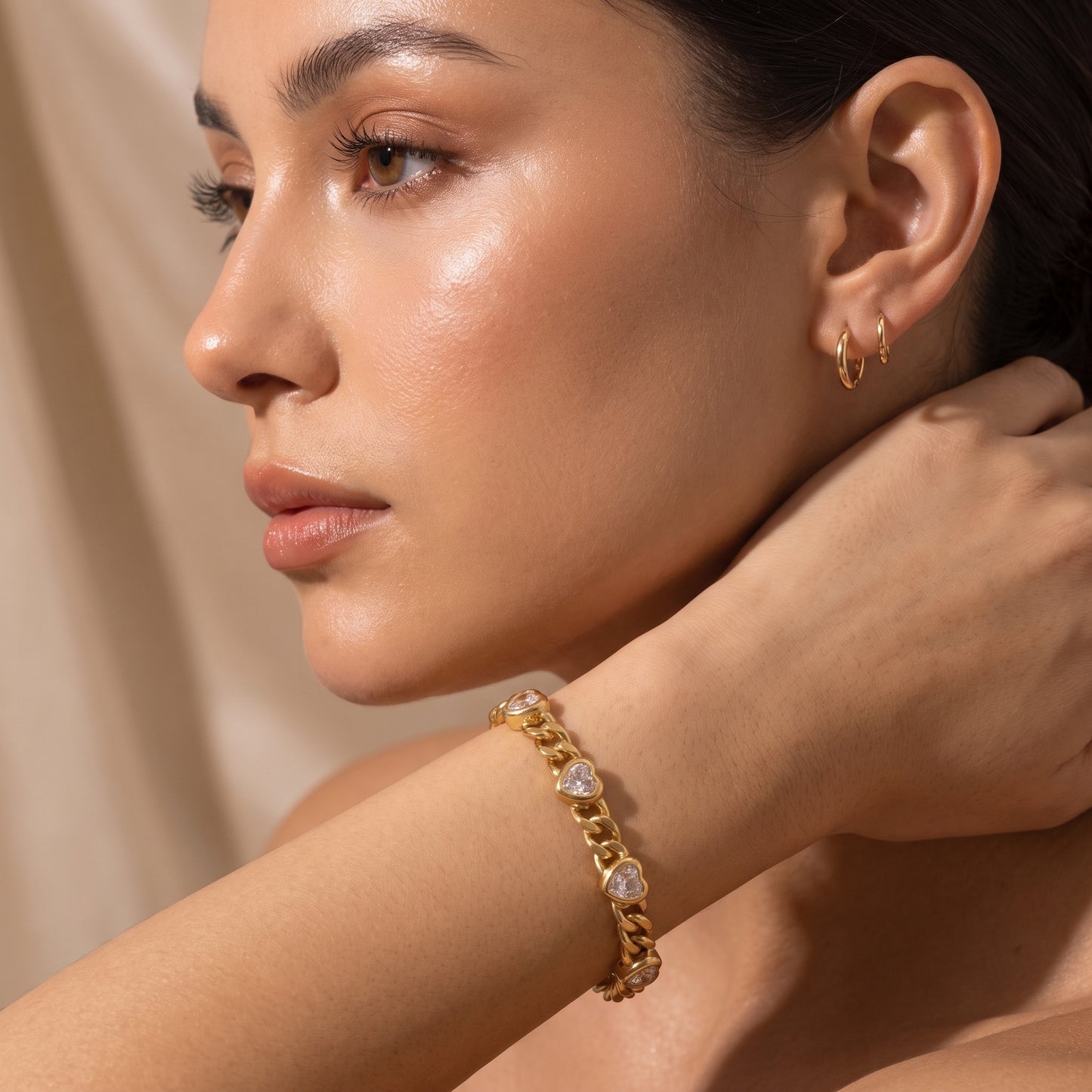 Close-up view of a woman's wrist wearing the waterproof Amour gold heart crystal curb chain bracelet in warm natural lighting.
