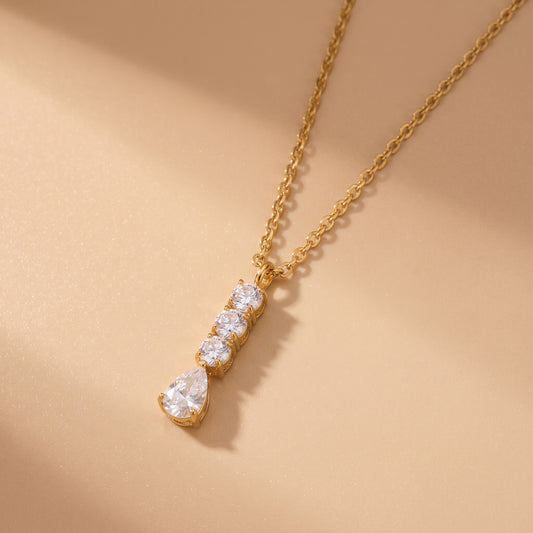 Extreme macro close-up of the tarnish-free Camille gold necklace showing prong-set round brilliant cubic zirconia stones and an articulated pear teardrop crystal.