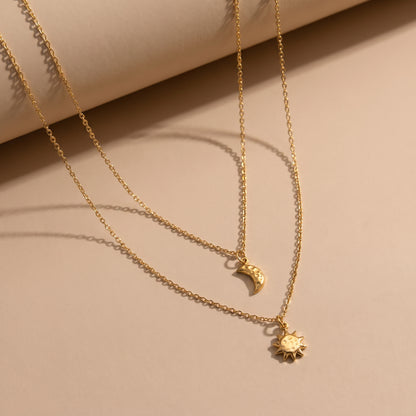 Extreme macro close-up view of the waterproof Céleste gold layered necklace showcasing the organic hammered textures of the crescent moon and sunburst pendants.