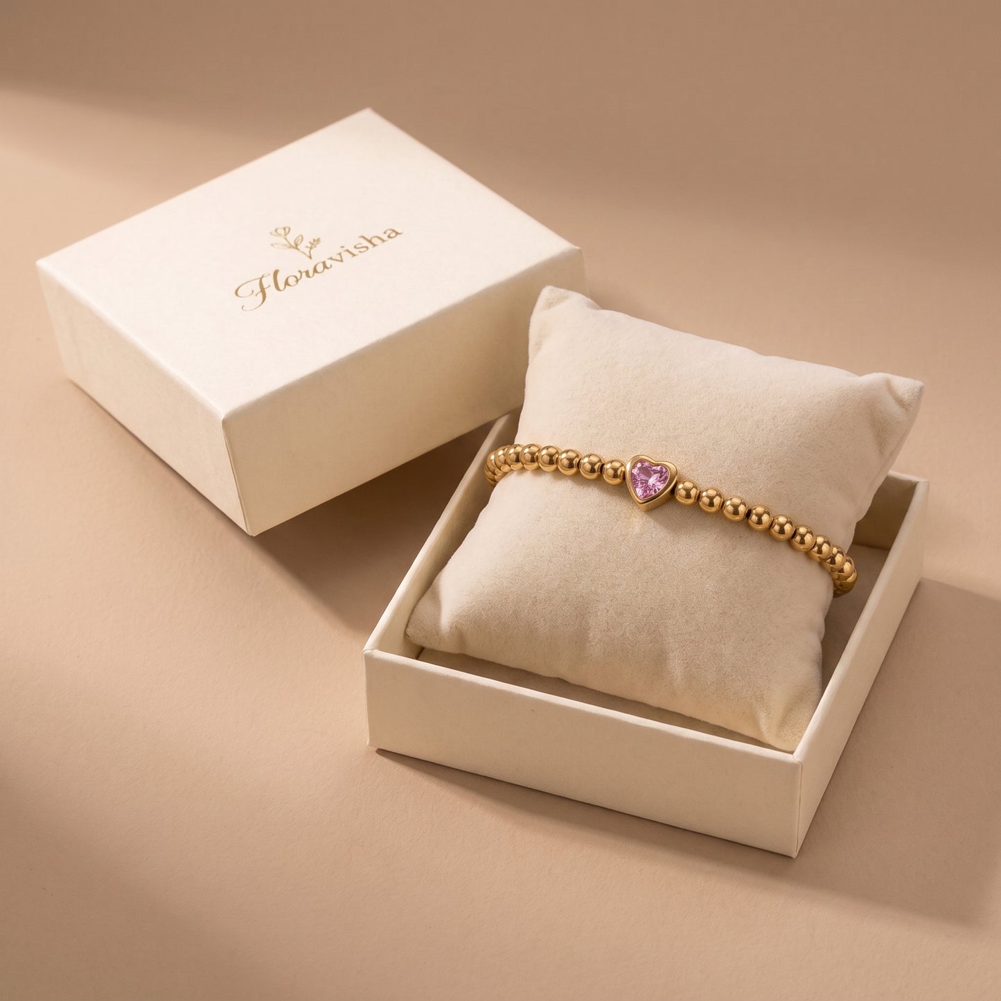 High quality Chérie gold pink heart crystal bead bracelet presented on a velvet pillow inside an off-white Floravisha luxury gift box.