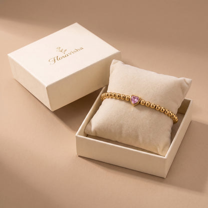 High quality Chérie gold pink heart crystal bead bracelet presented on a velvet pillow inside an off-white Floravisha luxury gift box.