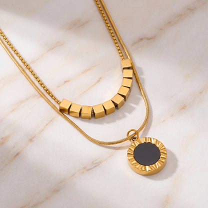 High quality waterproof gold plated double layer necklace featuring gold cube accents and a black natural stone pendant on a marble surface