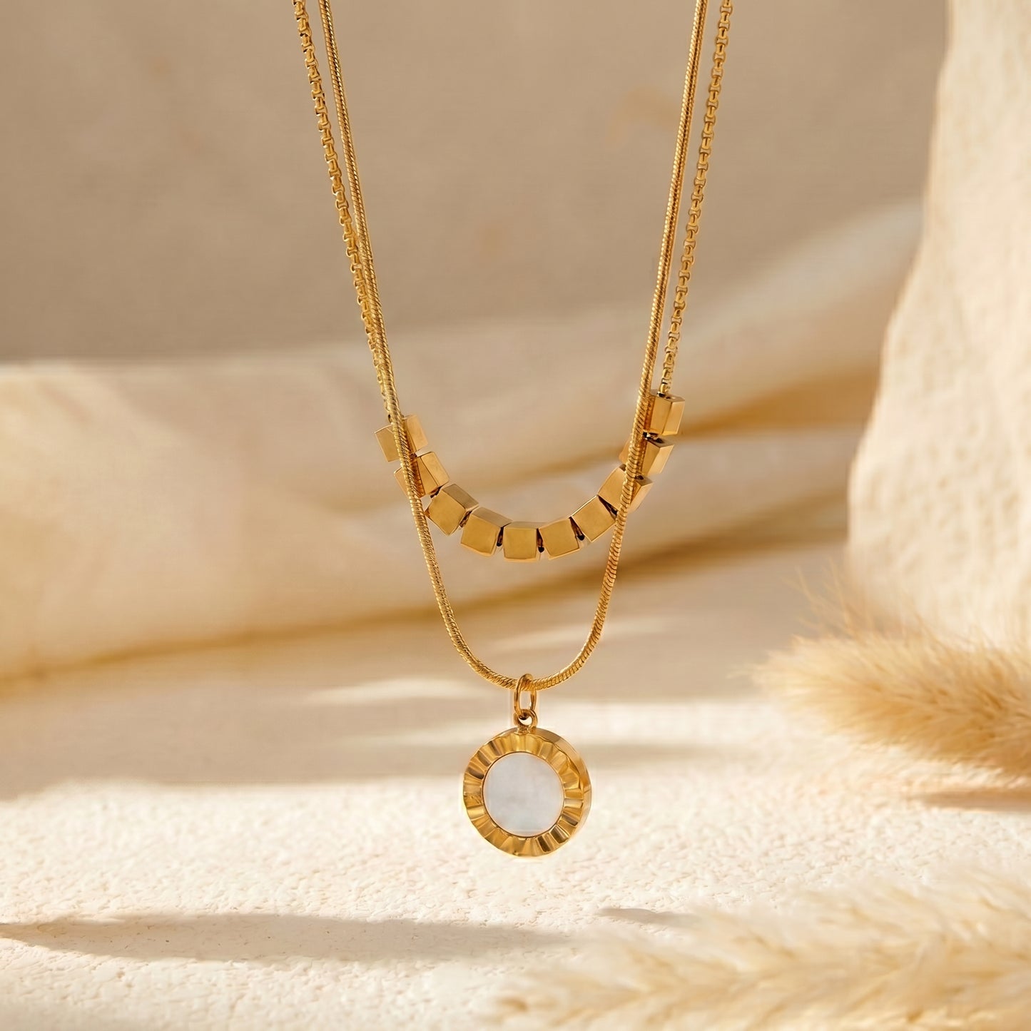 High quality waterproof gold plated double layer necklace featuring gold cube accents and a black natural stone pendant on a beige background