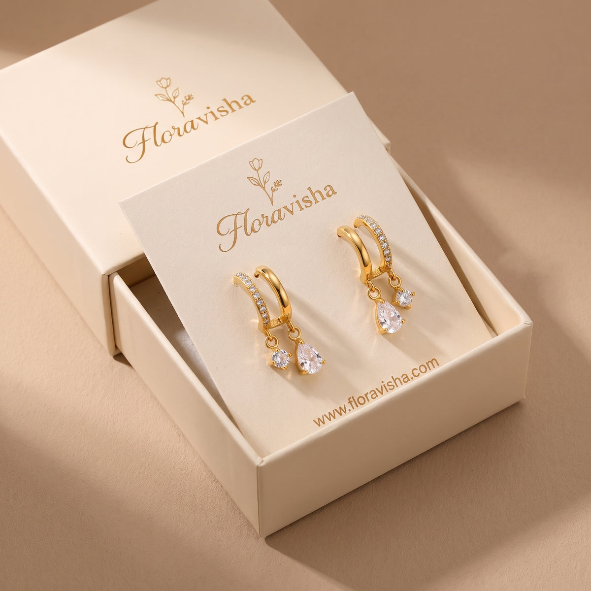 High quality Delphine gold dual-arch crystal drop earrings mounted on an elegant Floravisha jewelry card inside an open luxury sliding gift box.