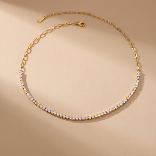 High quality Étoile gold half tennis choker necklace by Floravisha featuring prong-set cubic zirconia crystals transitioning into a paperclip link chain on a warm beige background.