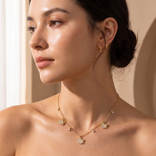 Close-up view of a woman's collarbone wearing the skin friendly Féline gold pavé cat silhouette necklace in warm natural sunlight.