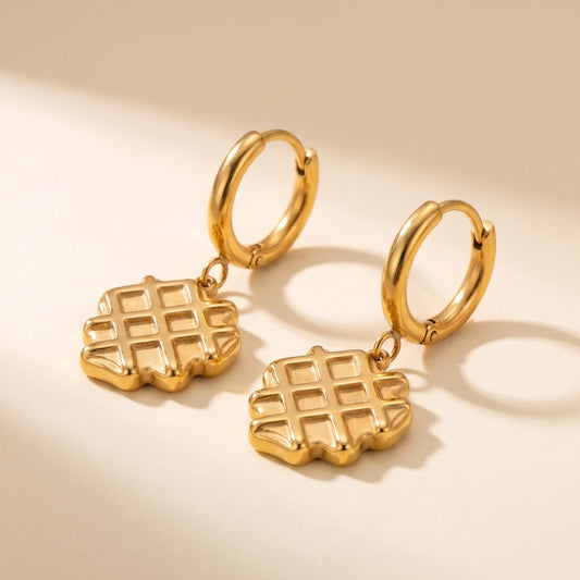 Detailed studio close-up of the tarnish-free La Gaufre gold waffle charm earrings showing scalloped edges and deep grid indentations.
