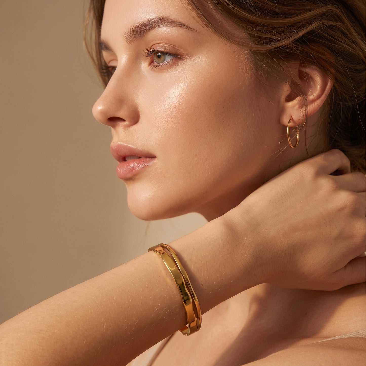 High quality Ondine gold double-layered organic wave cuff bangle worn on a model's wrist in warm studio lighting.