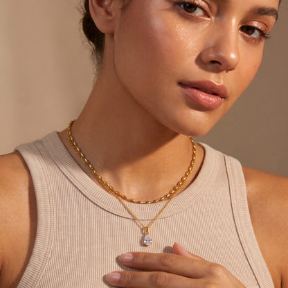 Close-up view of a woman's collarbone wearing the skin friendly Seraphine gold layered necklace with upper oval bead choker and crystal teardrop pendant.