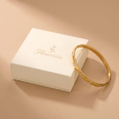 Waterproof Solene gold flush-set crystal bracelet resting beside an elegant off-white Floravisha branded luxury jewelry gift box.