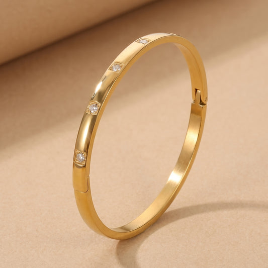 High quality Solene Gold Bracelet by Floravisha featuring flush-set clear cubic zirconia crystals resting on a warm beige surface in natural sunlight.