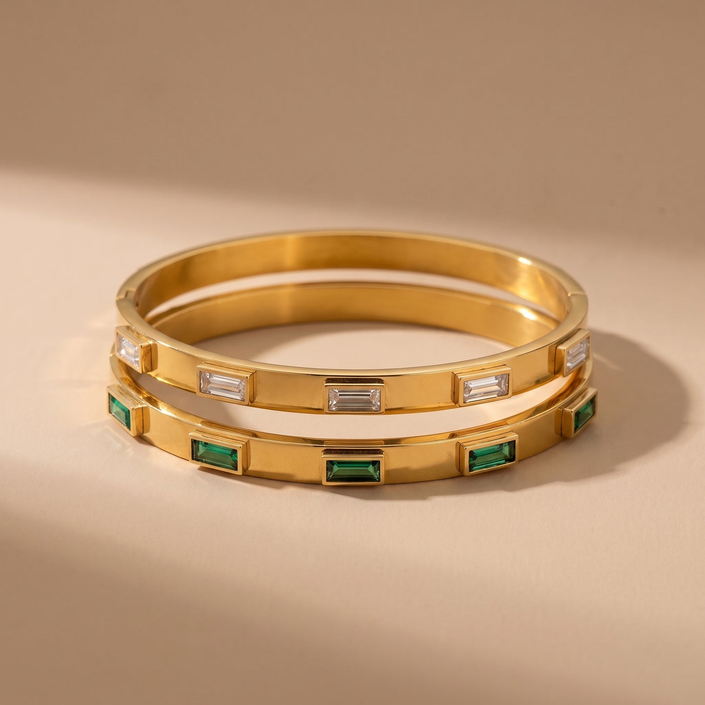 High quality Verona Gold Bracelets by Floravisha featuring raised bezel-set clear baguette crystals resting on a warm beige travertine surface under natural sunlight.
